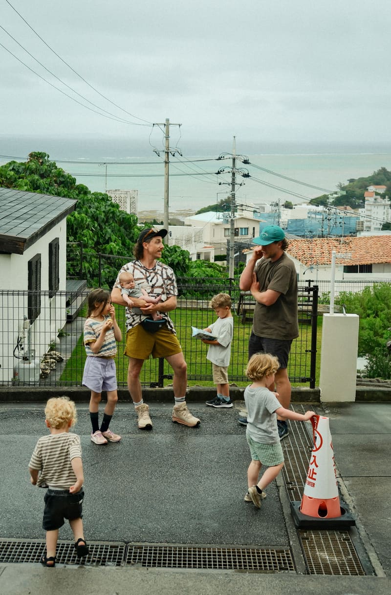Two fathers with their children on a street above the sea in Okinawa